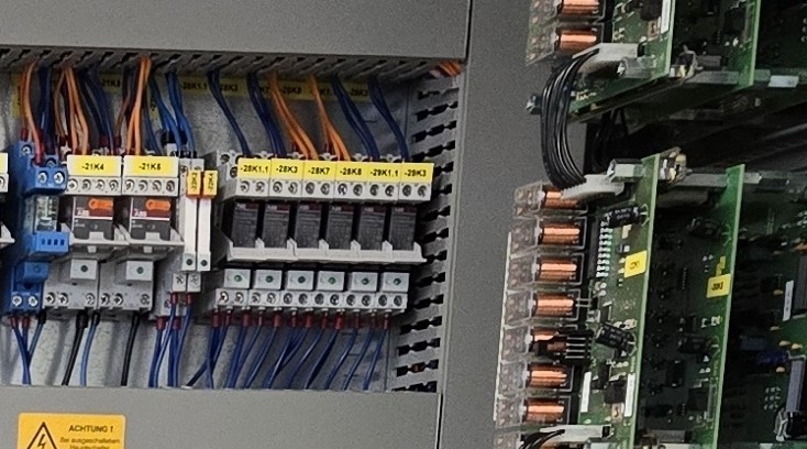 Elektrischer Schaltschrank mit beschrifteten Sicherungen, Kabeln und Leiterplatten in einem Industriegerät
