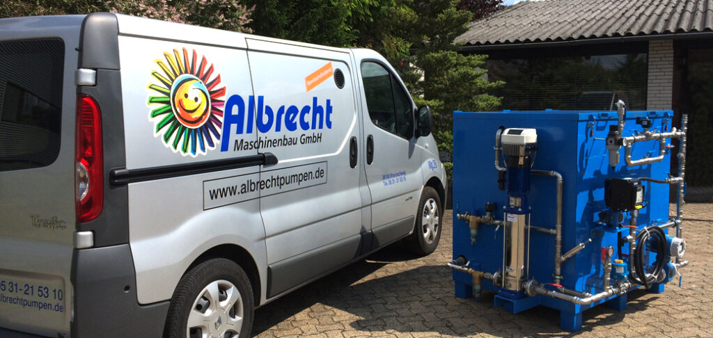 Weißer Transporter mit Logo von Albrecht Maschinenbau GmbH neben einer blauen Industriemaschine im Freien