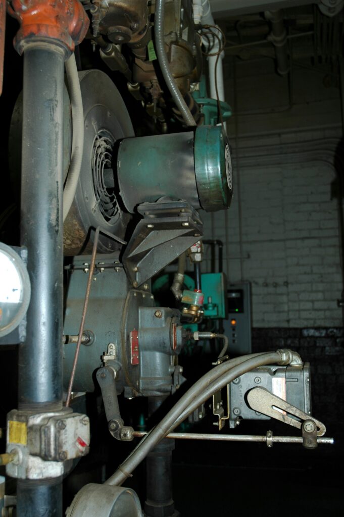 Industrielle Maschine mit Ventilator und Rohrleitungen in einer dunklen Fabrikumgebung