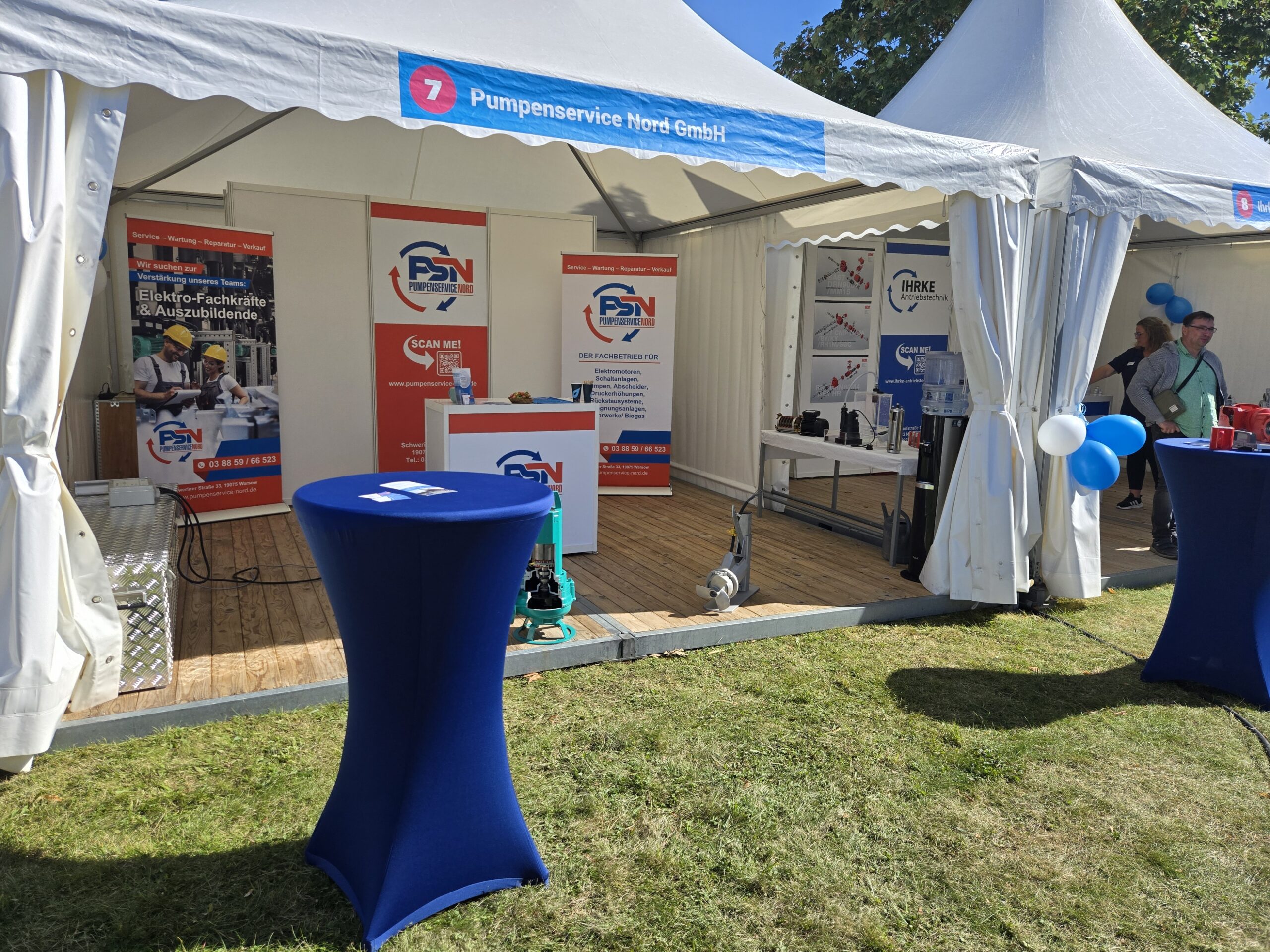 Messestand der Pumpenservice Nord GmbH mit Informationsständen, Bannern und blauen Stehtischen im Freien unter einem weißen Zelt