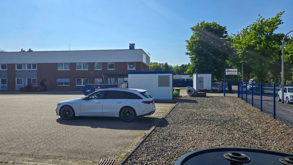 Silberner Kombi auf Parkplatz vor zweistöckigem Albrechtgebäude mit braunen und weißen Fassaden