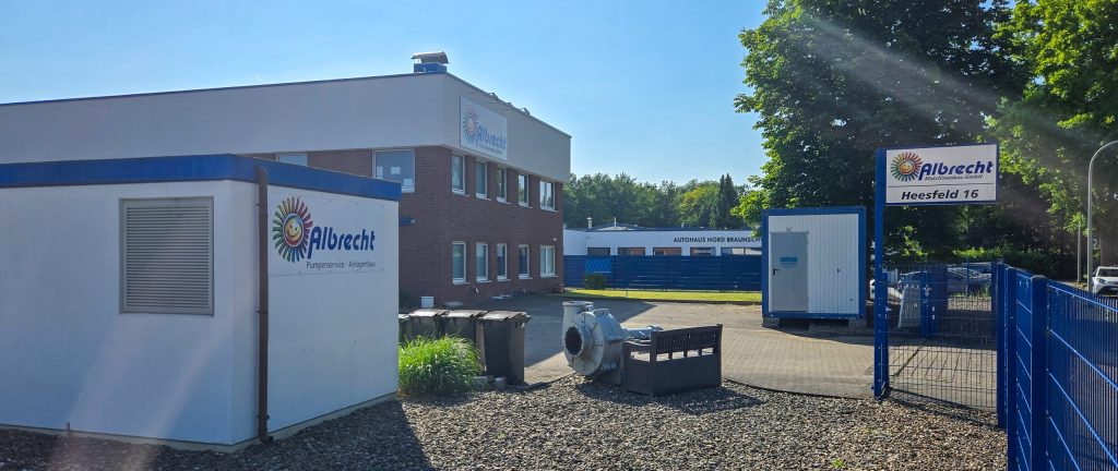 Firmengelände von Albrecht Maschinenbau mit Bürogebäude, Lagercontainern und Eingangstor mit Firmenschild