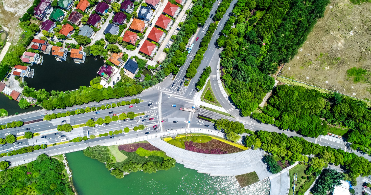Luftaufnahme einer Stadt mit Wohnhäusern, Straßenkreuzung, Grünflächen und einem See