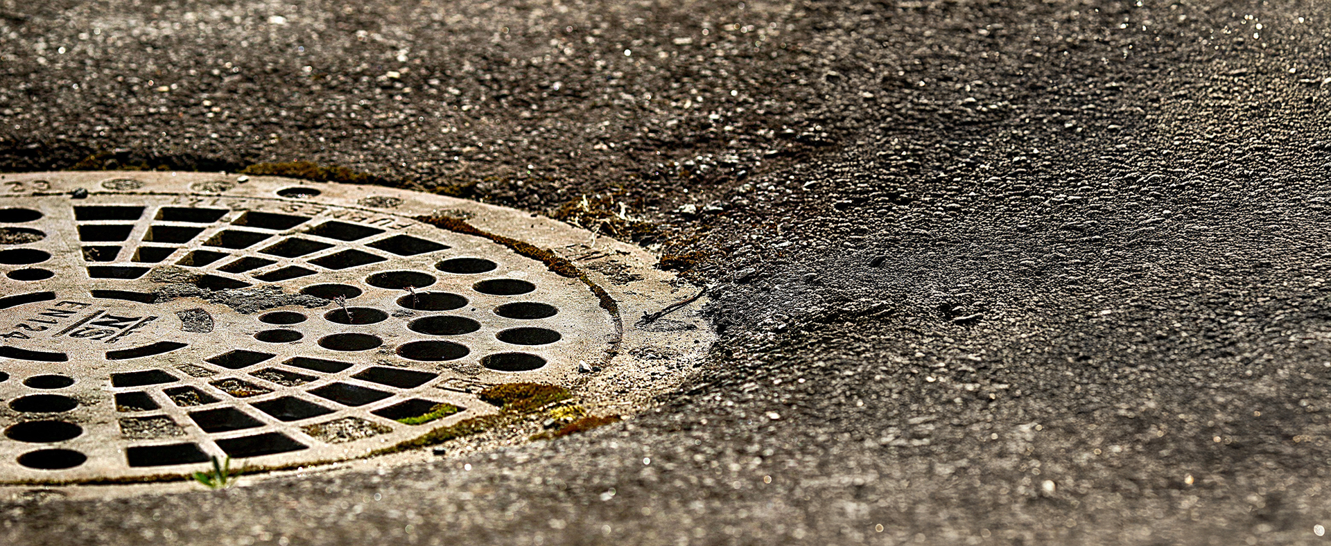 Runder Abdeckungsdeckel mit Löchern auf Asphalt, Teil eines Abscheidersystems