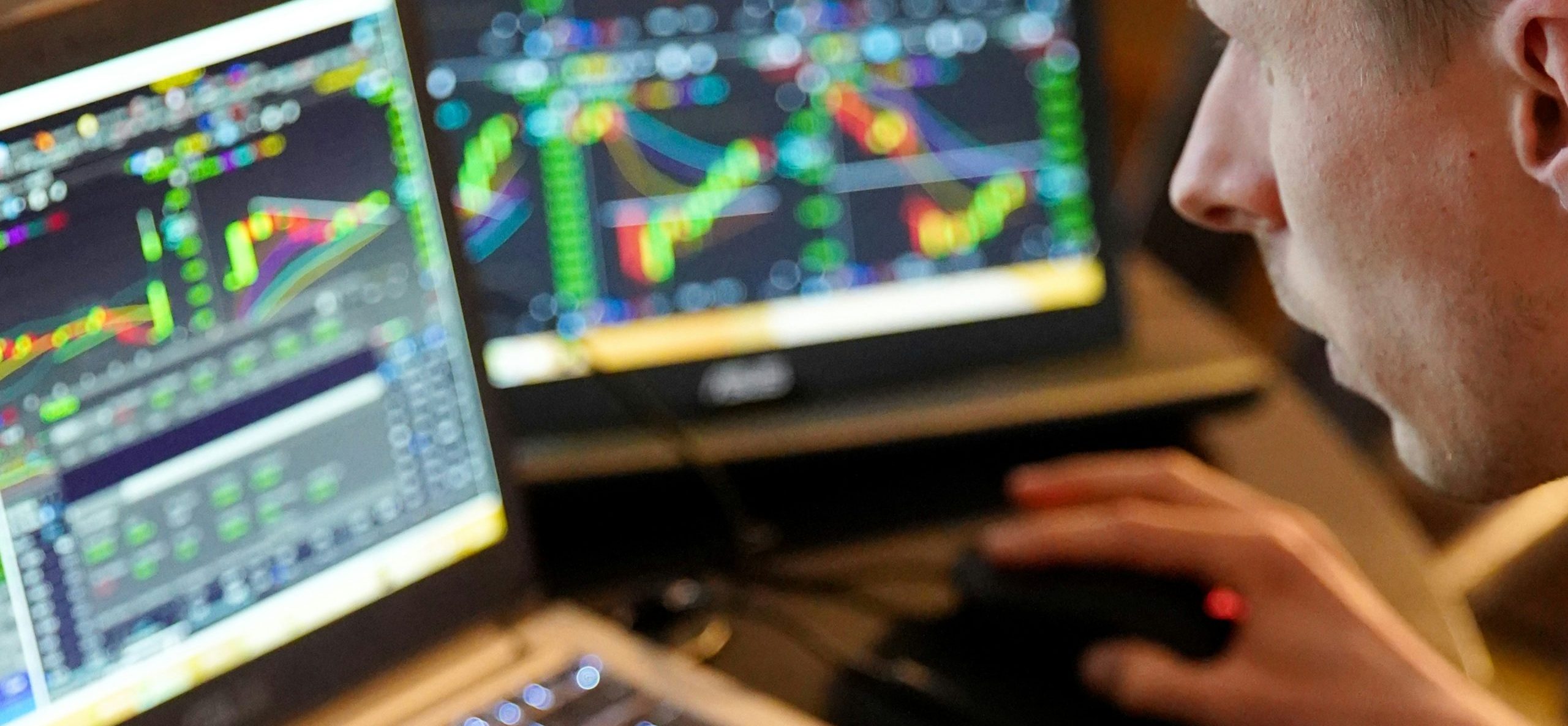 Person bedient Computermaus vor zwei Monitoren mit bunten Diagrammen und Daten, vermutlich zur Pumpenauslegung.