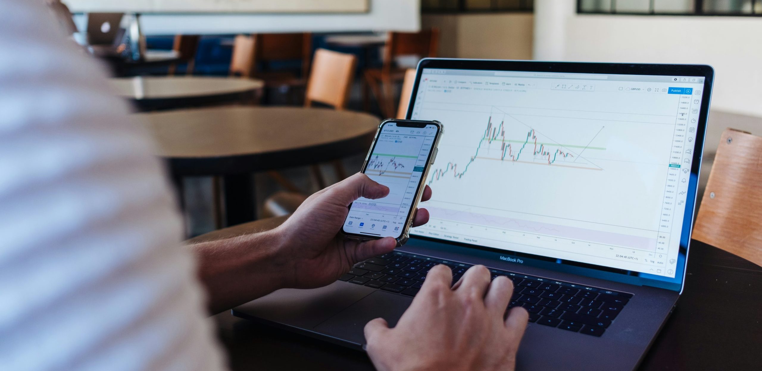 Person hält Smartphone mit Pumpenüberwachung vor Laptop mit ähnlichem Diagram