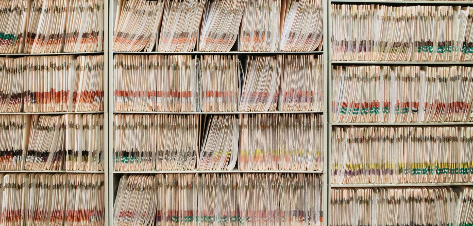 Regale voller Aktenordnern mit Vorschriften und sichtbaren farbigen Markierungen auf den Rücken.