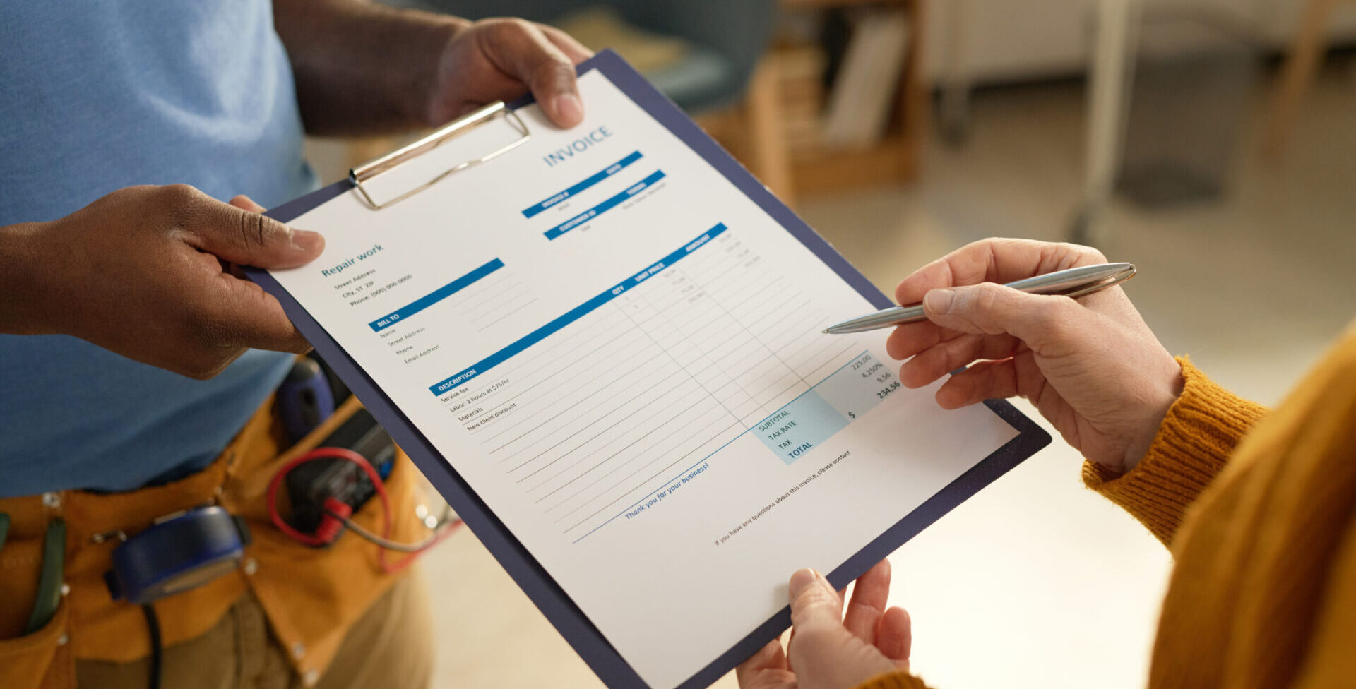 Zwei Personen halten gemeinsam ein Klemmbrett mit einem Wartungsvertrag, eine Person zeigt mit einem Stift auf das Dokument.