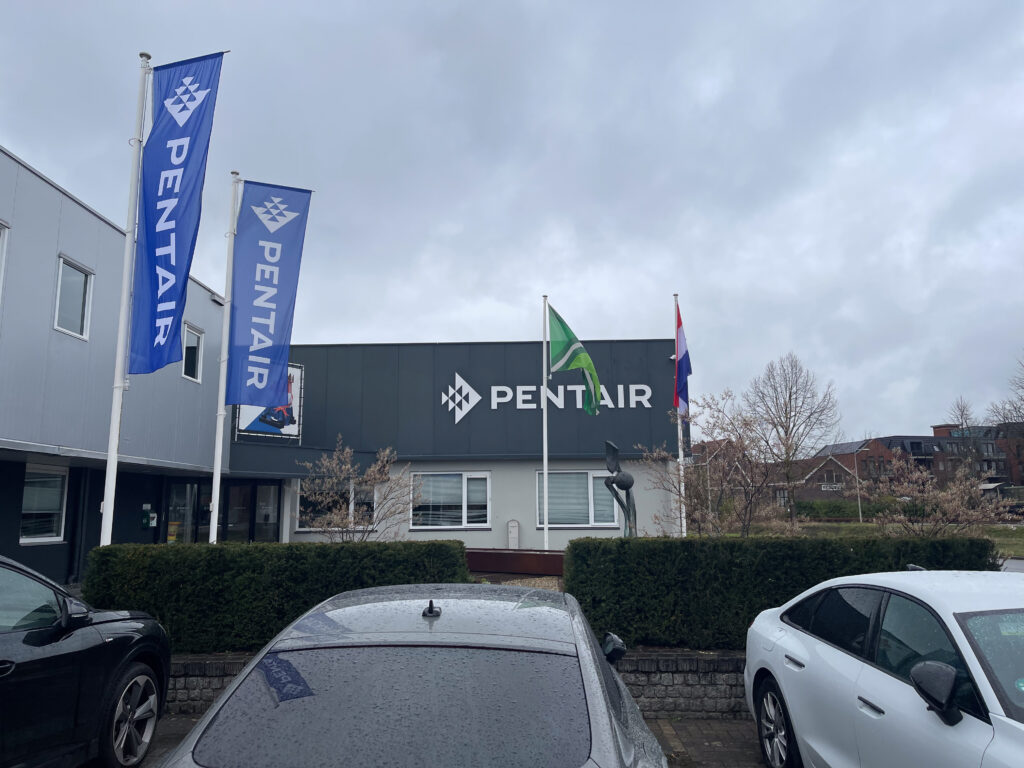 Pentair-Gebäude mit mehreren Fahnen und geparkten Autos im Vordergrund